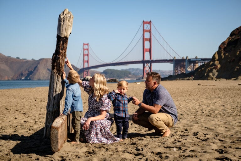 Mom, dad, and two sons play on beach in front of Golden Gate Bridge
