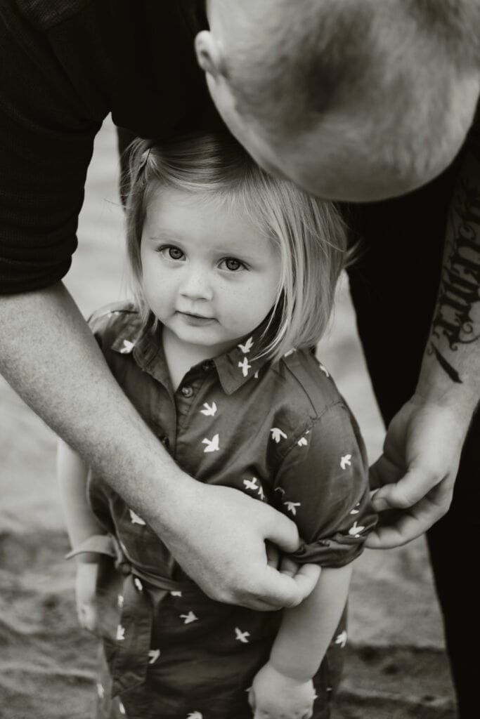 Dad with tattoos rolls his daughter's sleeve.