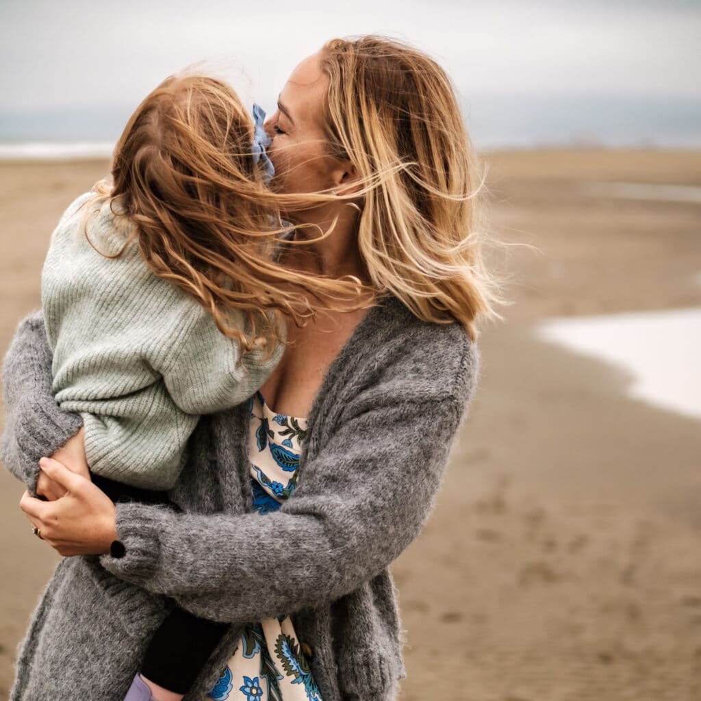 Mom holds daughter on the beach