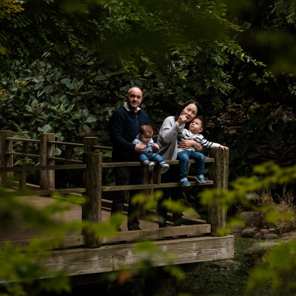 Family of four sitting on a platform above a pond