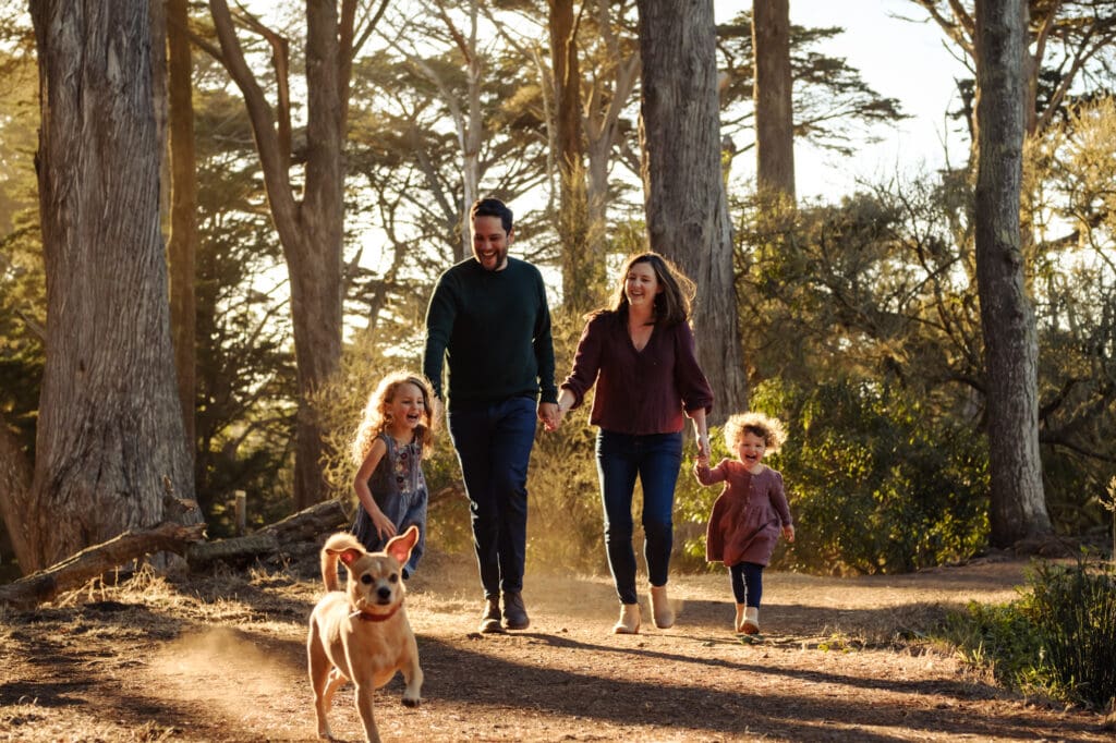 Family of 4 in Fall colors run behind their dog.