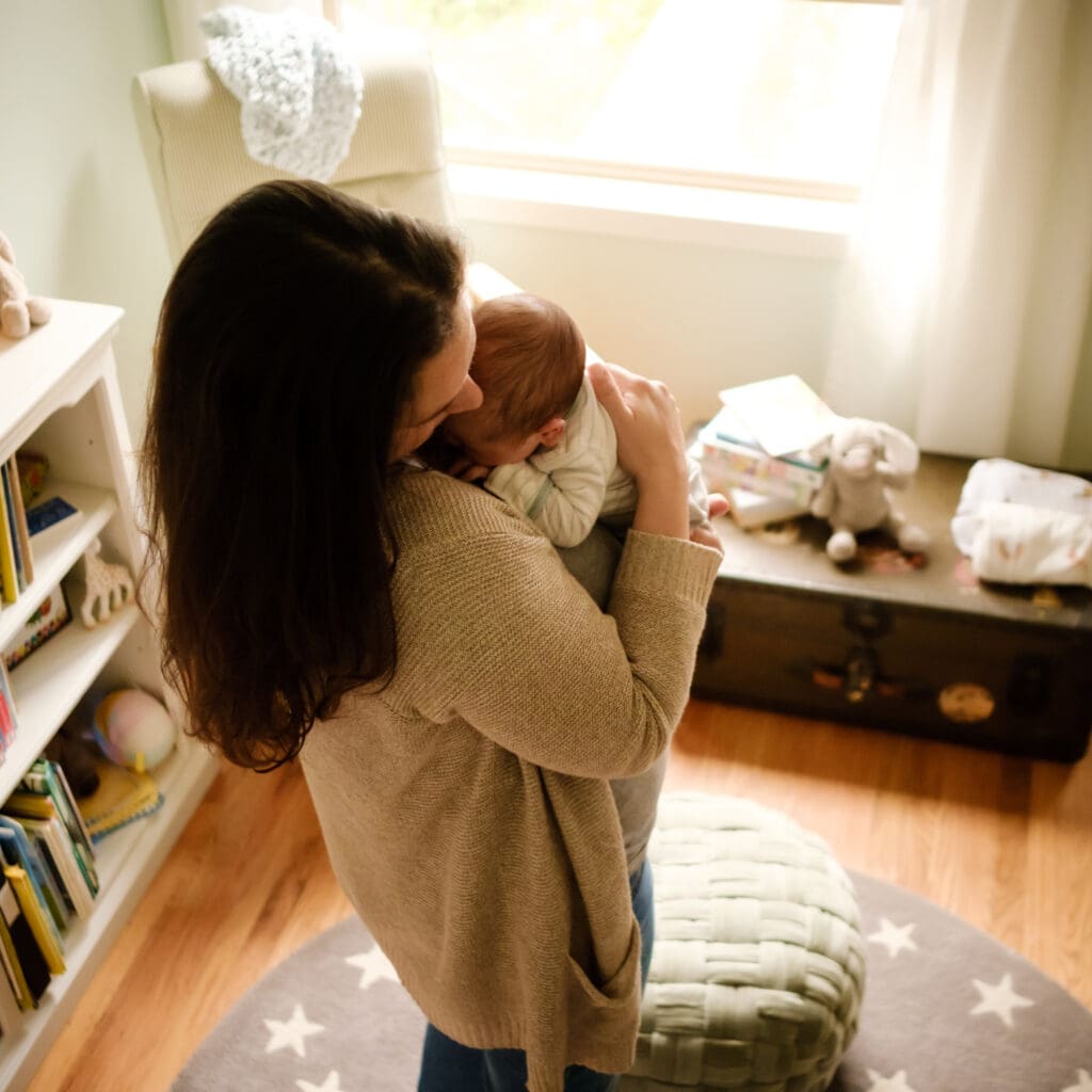 Mom holds newborn in home nursery