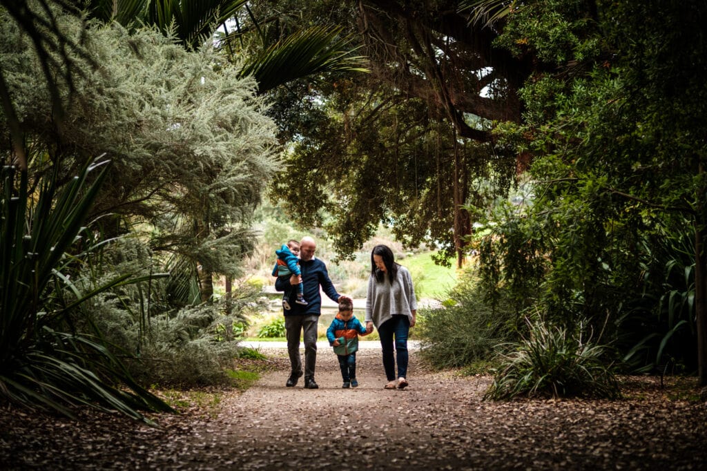 family of four walks together through a dense tree tunnel.