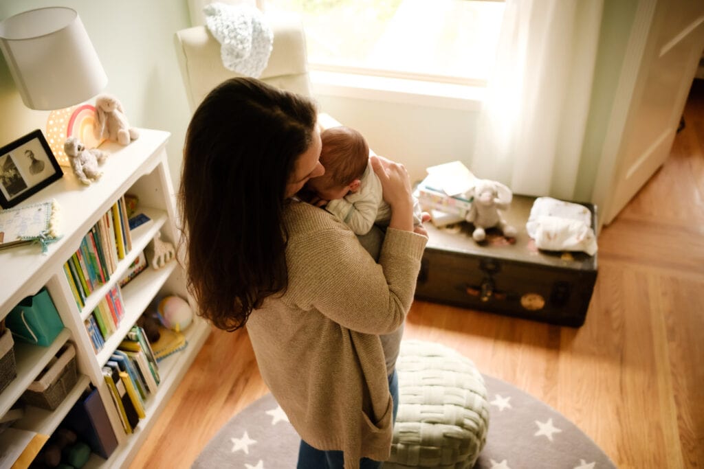 Mother holds newborn in home nursery