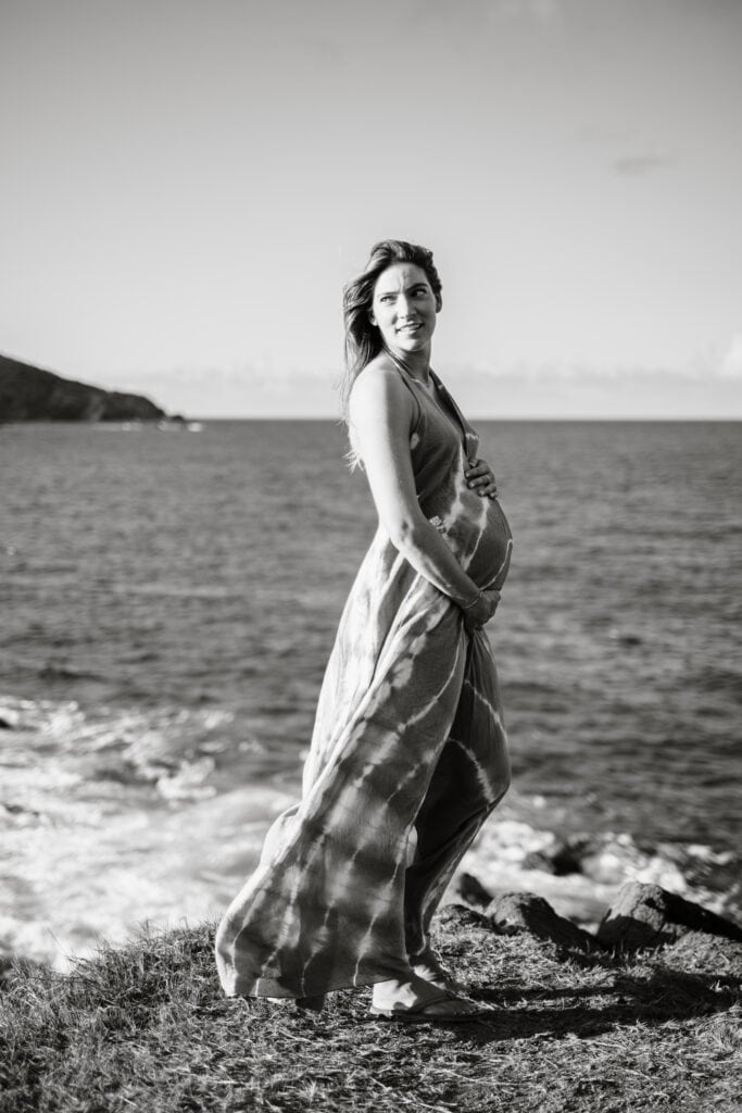Woman holds her pregnant bump while wind blows through her dress
