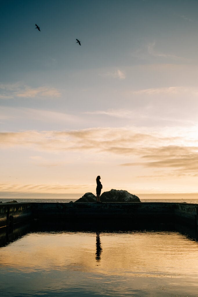 Silhouette of a pregnant woman reflected in the sunset light at the iconic Sutro Baths of San Francisco.