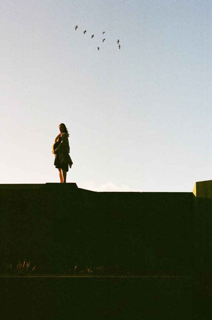 Silhouette of pregnant woman on top of old military battery at sunset.