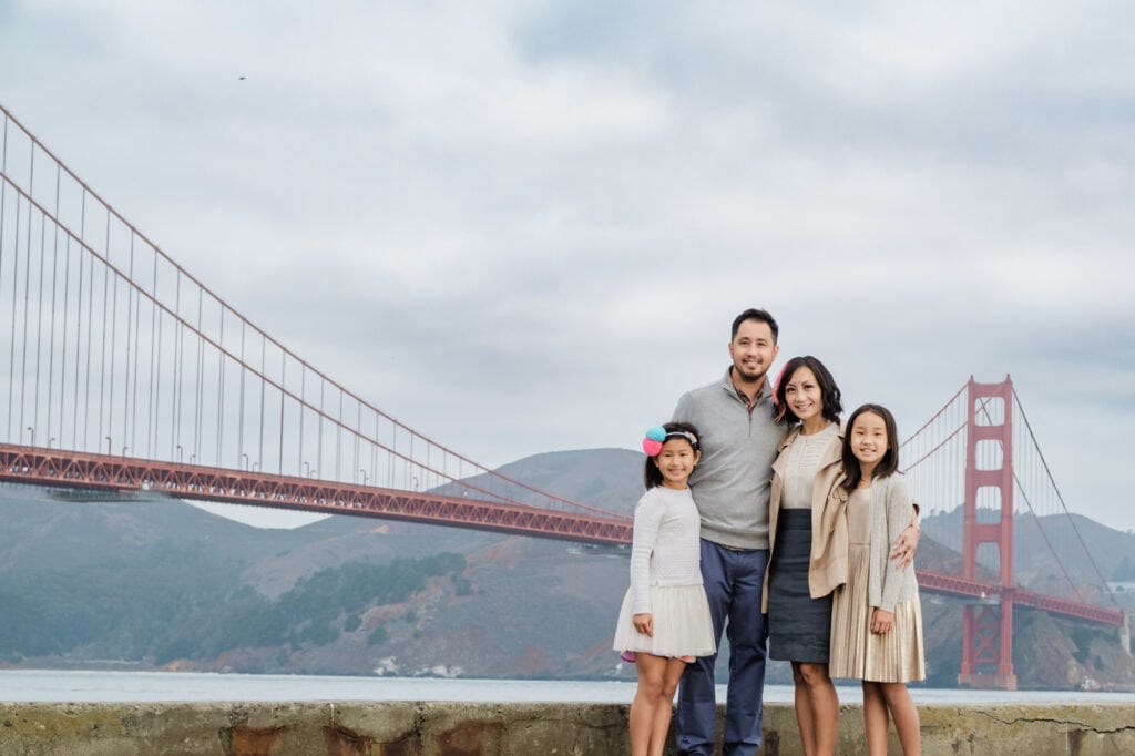 Family poses for a photo in front of the Golden Gate Bridge.