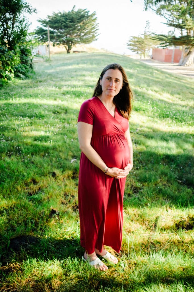 Portrait of pregnant woman in grassy field.