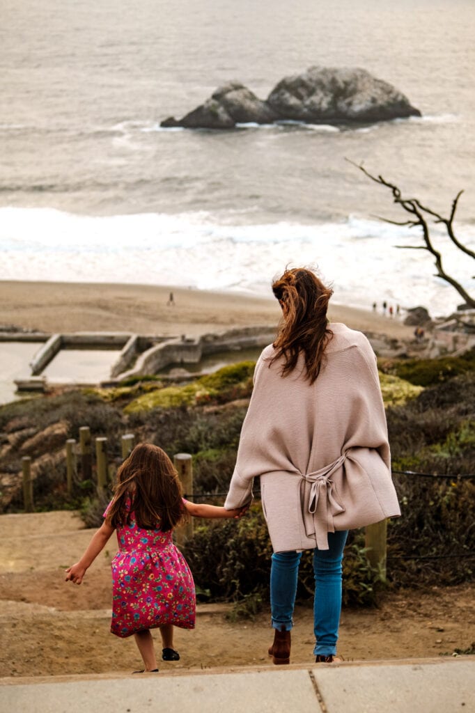 Mom walks daughter down stairs towards the famous pools of Sutro Baths in San Francsico.