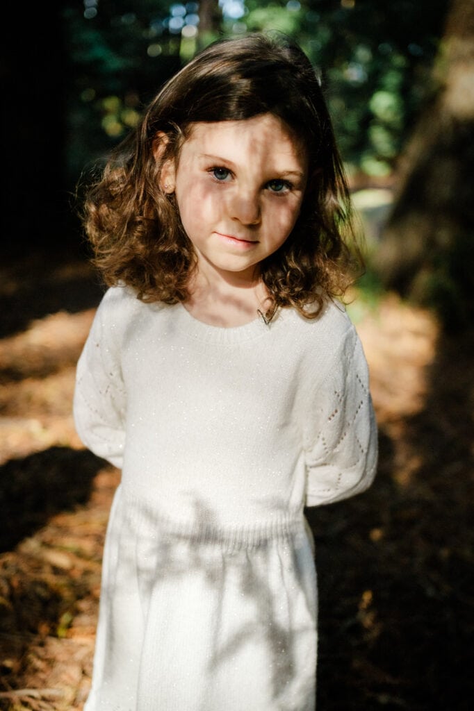 Redwood leaf shadows fall across a young girl's face.