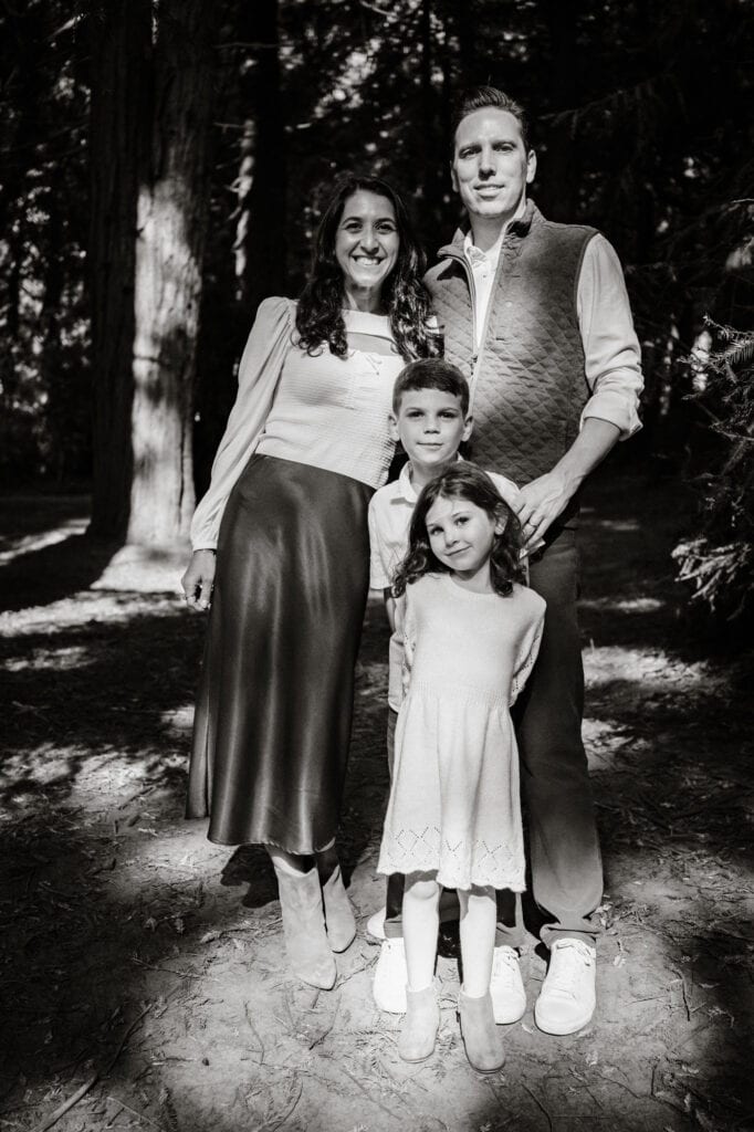 Family portrait in black and white with dappled forest sunlight.