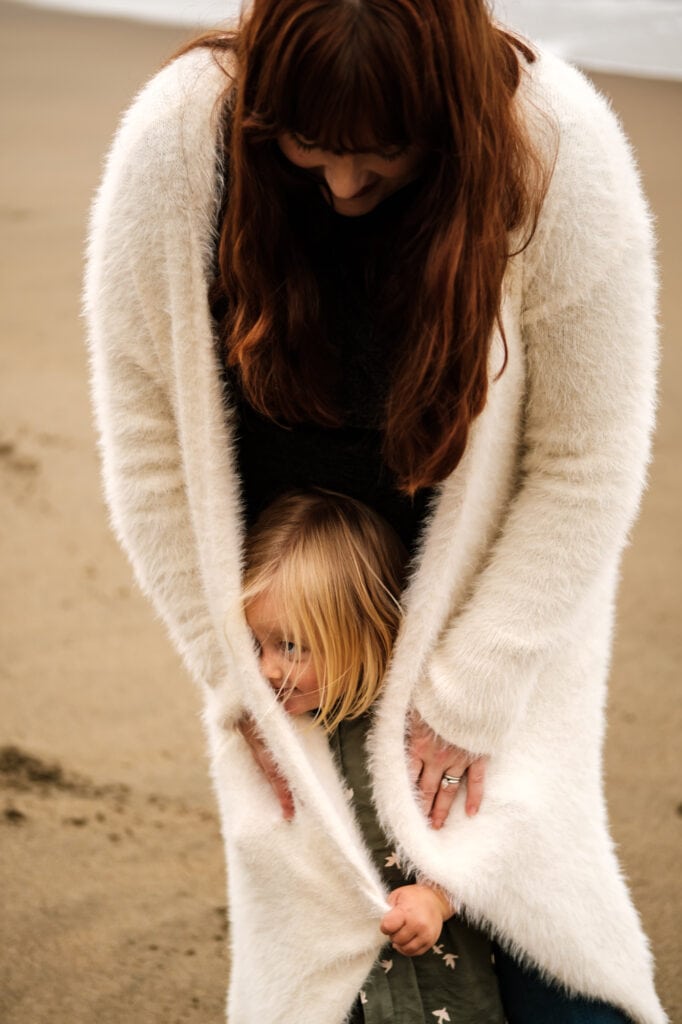 Daughter hides in mom's fur coat.