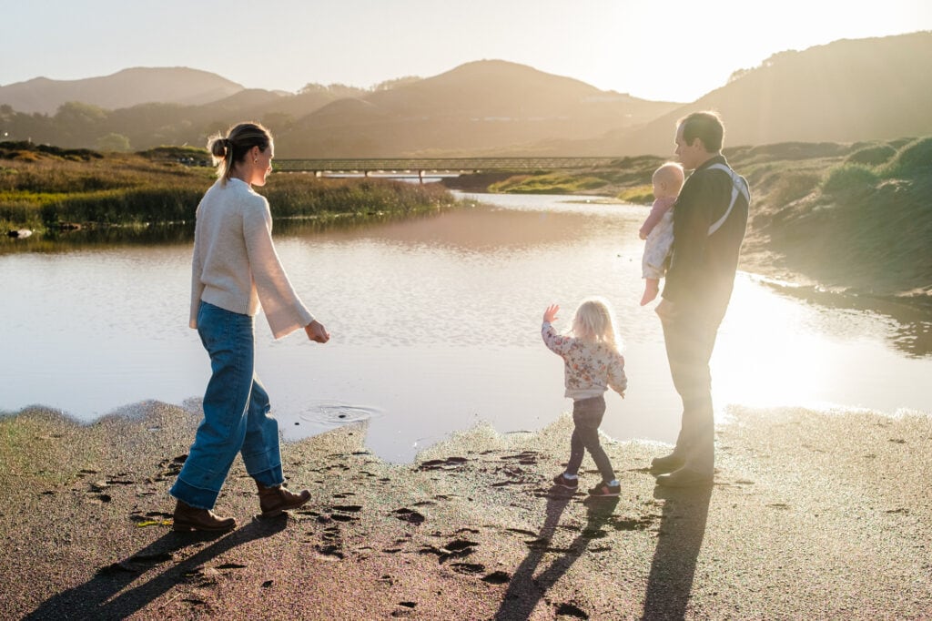 Family stands backlit in front of a sandy marsh in low, winter light.