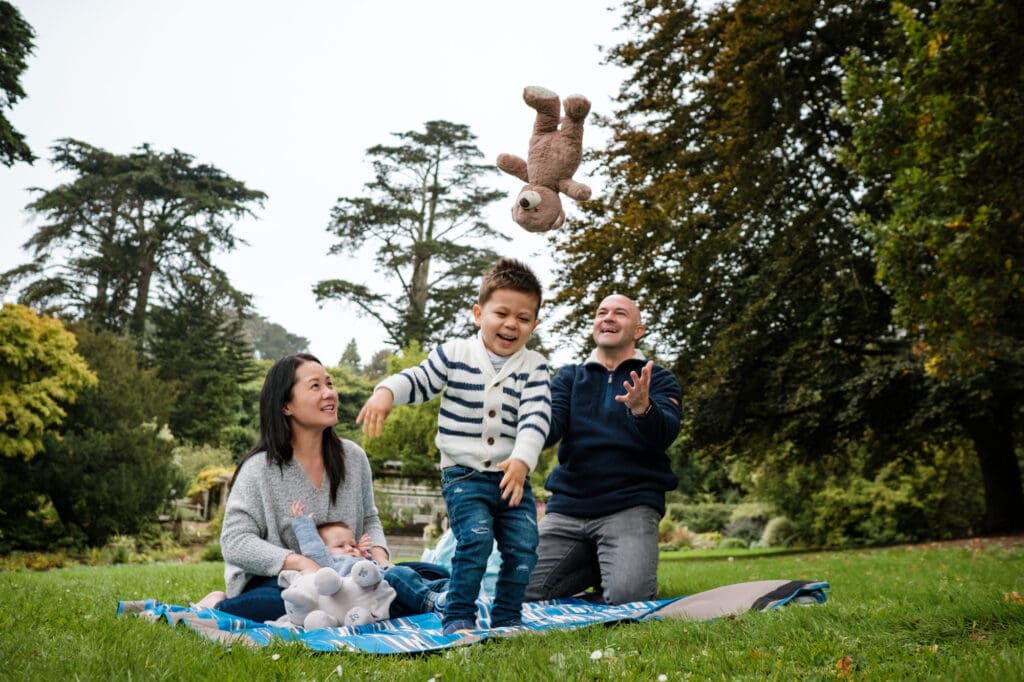 Toddler and family play on a blanked on a lawn.