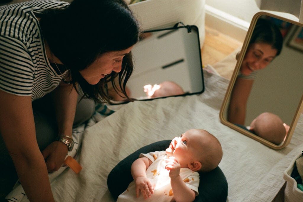 Mom interacting with newborn baby, reflected in a mirror