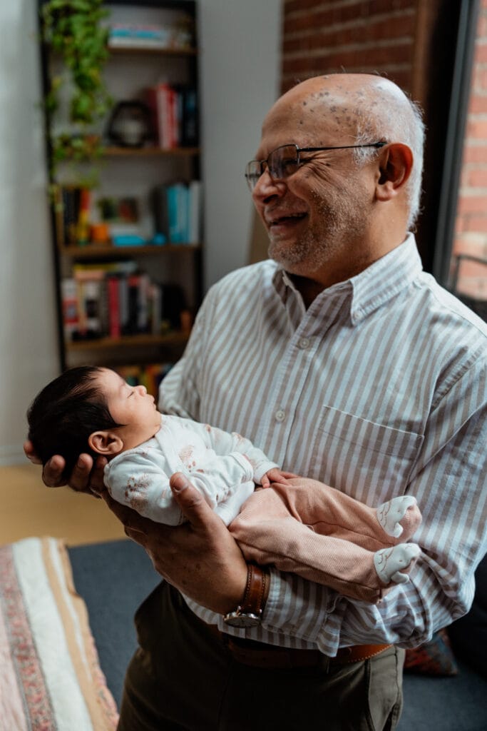 Grandfather holding newborn and laughing.