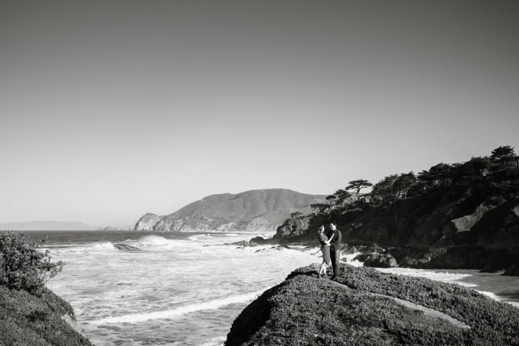 Couple embracing at the end of the trail right above the ocean.