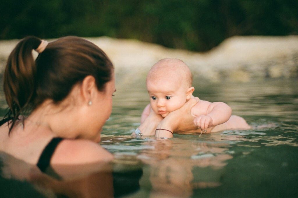 Mom holding a 6 week old as she floats in the ocean