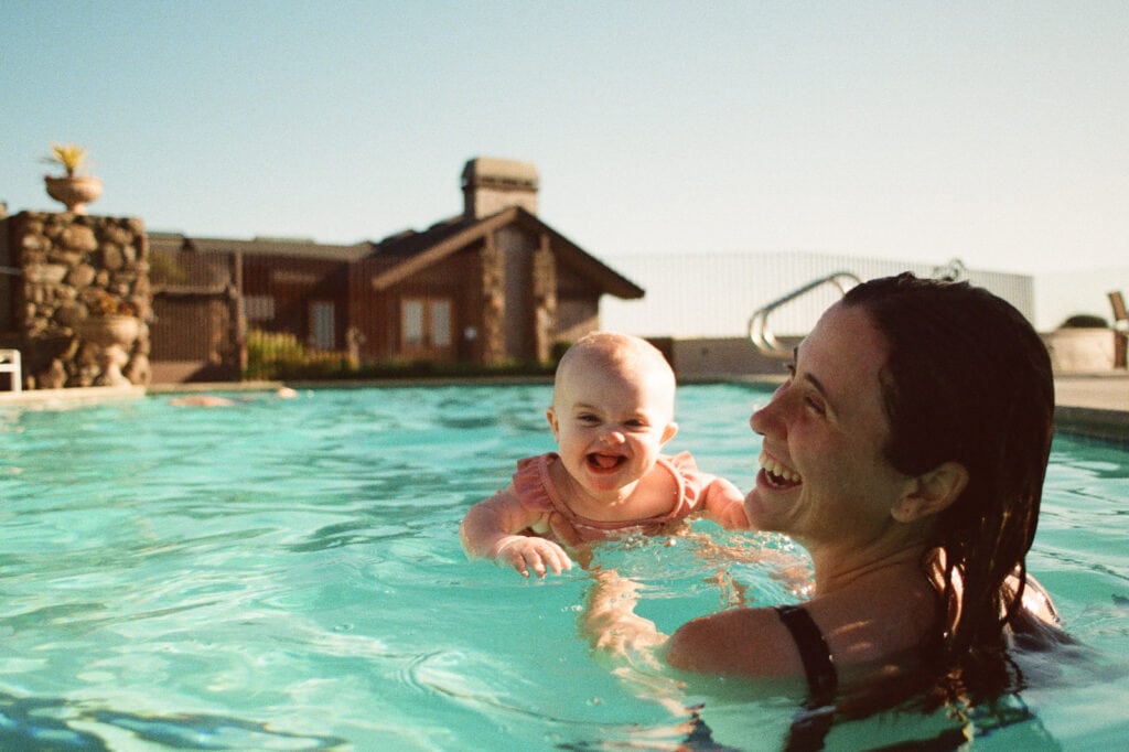 Baby in pool with mom gives huge toothless grin